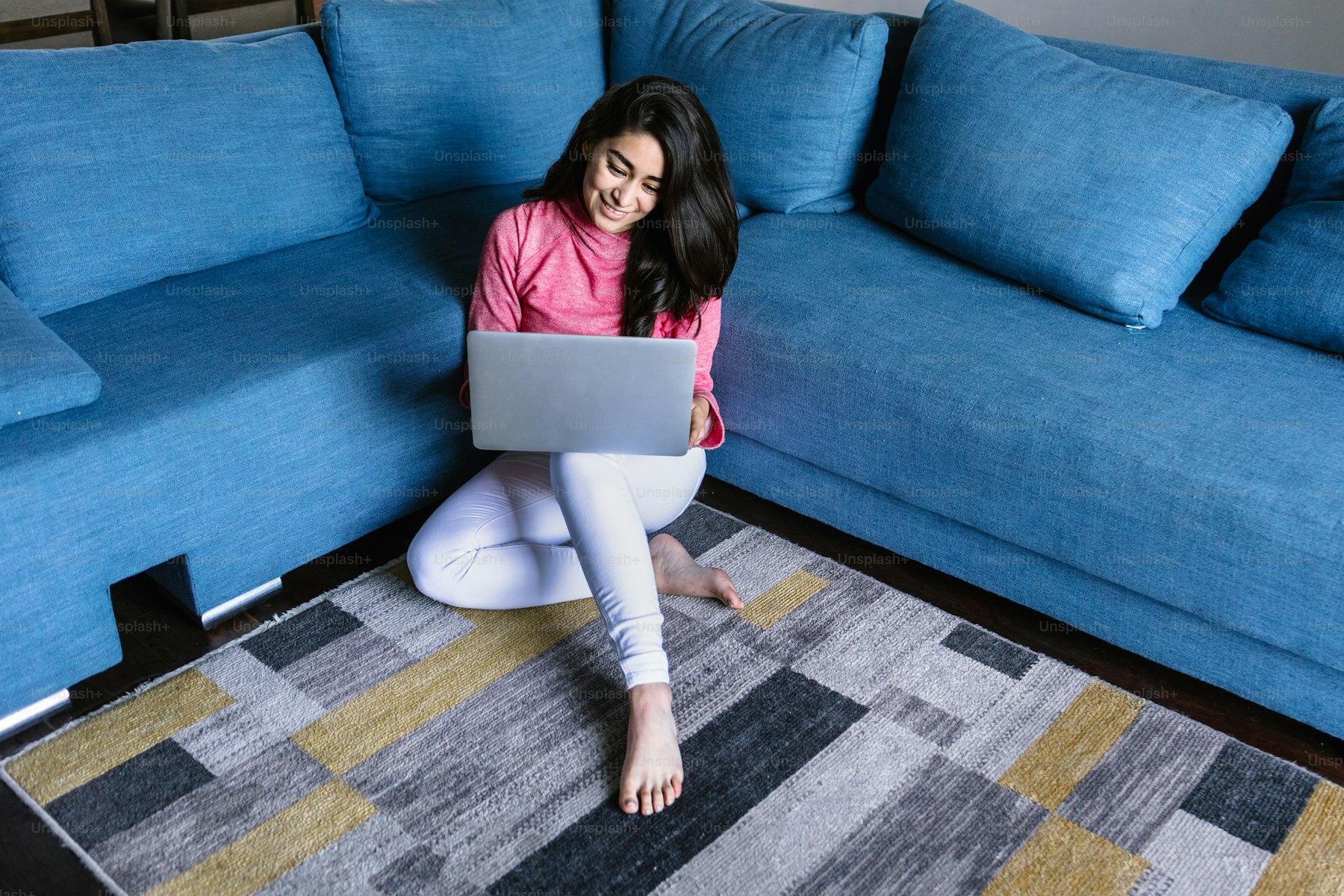 Hands cradling a warm mug beside a laptop on a kitchen table in soft morning light